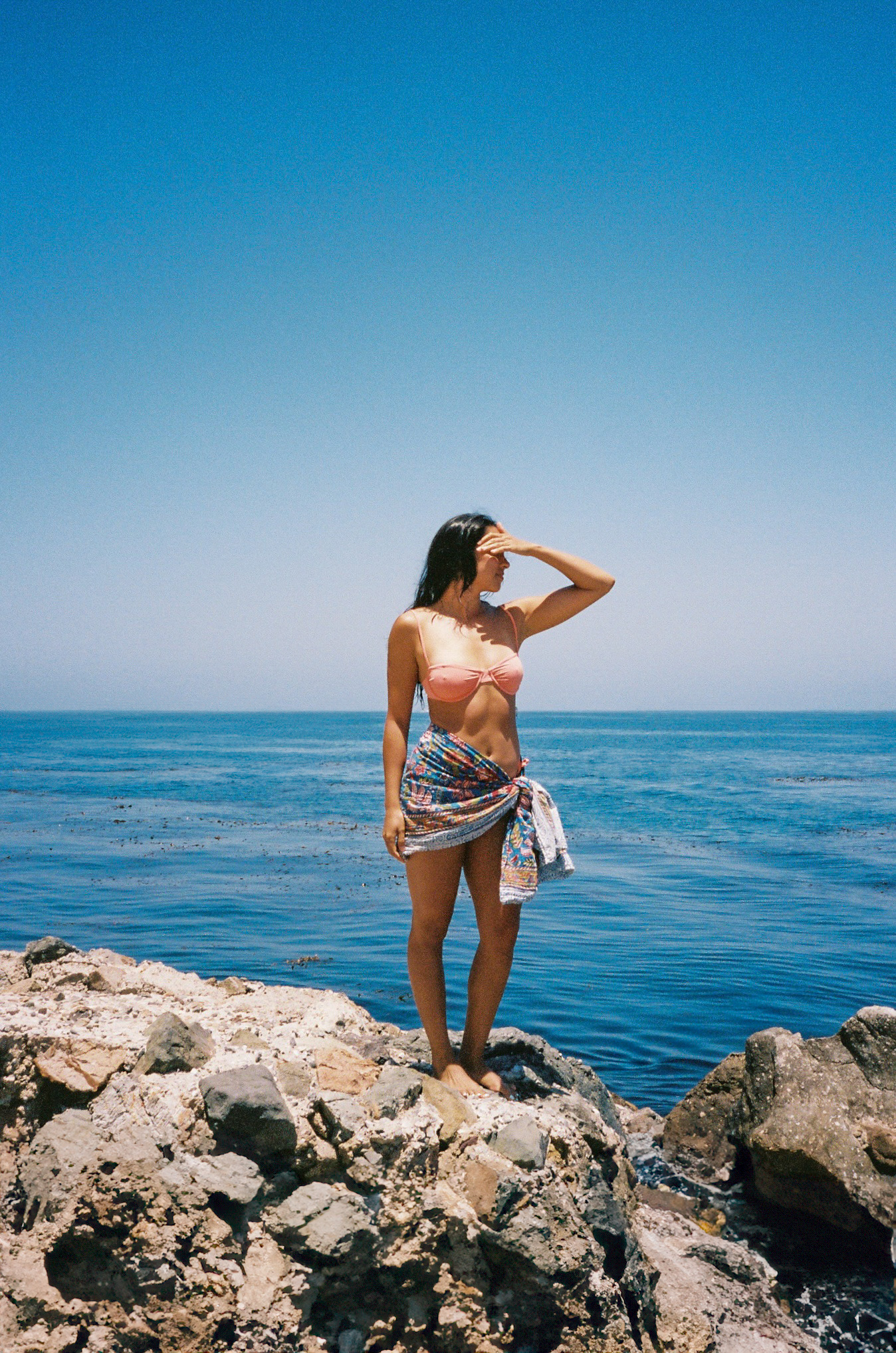Woman standing on shoreline rocks beside the sea