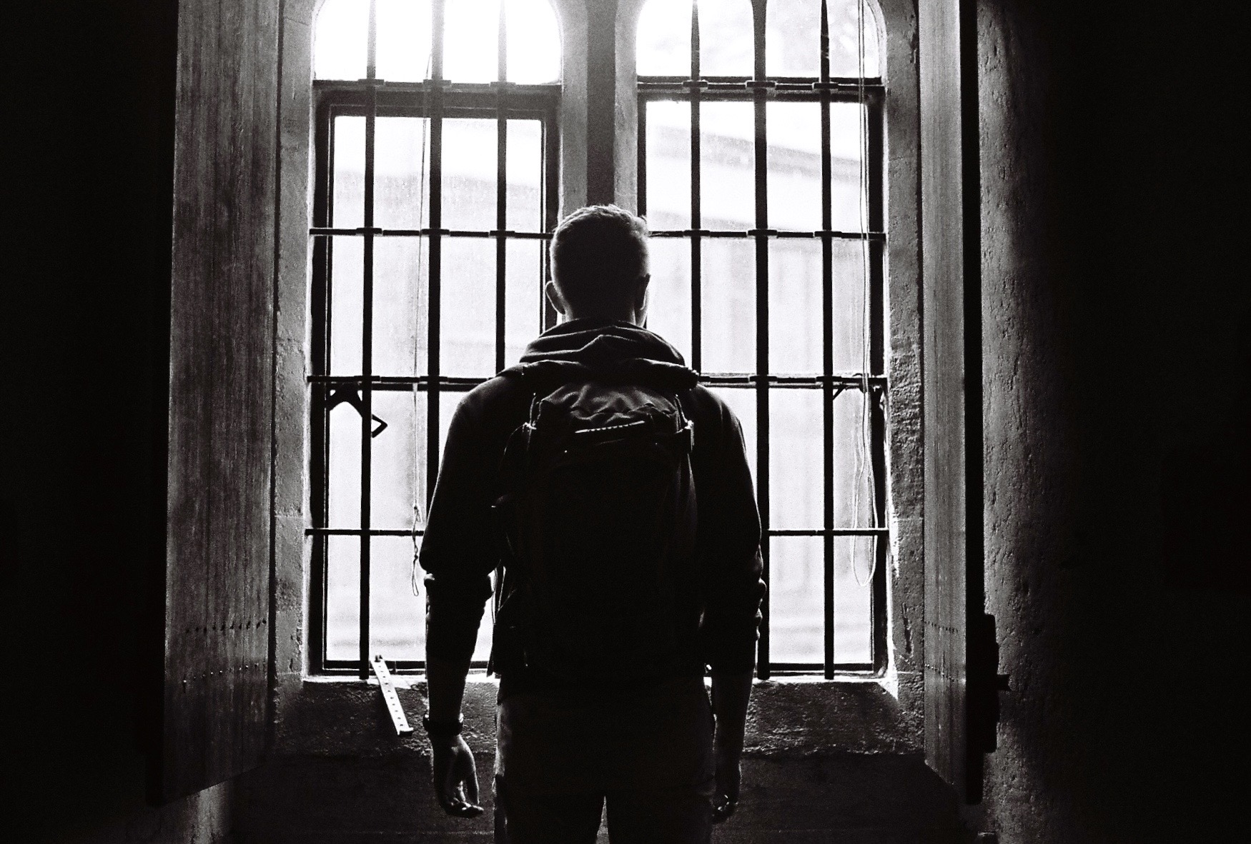 Backlit figure facing a tall window